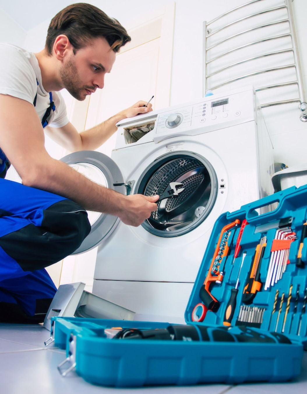 A man engaged in repairing a washing machine, illustrating appliance repair services in Renton, WA.