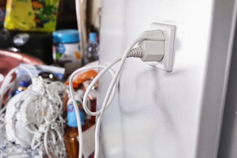 Detailed view of a refrigerator's power cord connection, highlighting common causes of circuit breaker tripping.