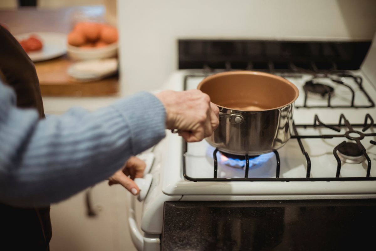 A person stands at a stove, cooking with a pot not heating properly.